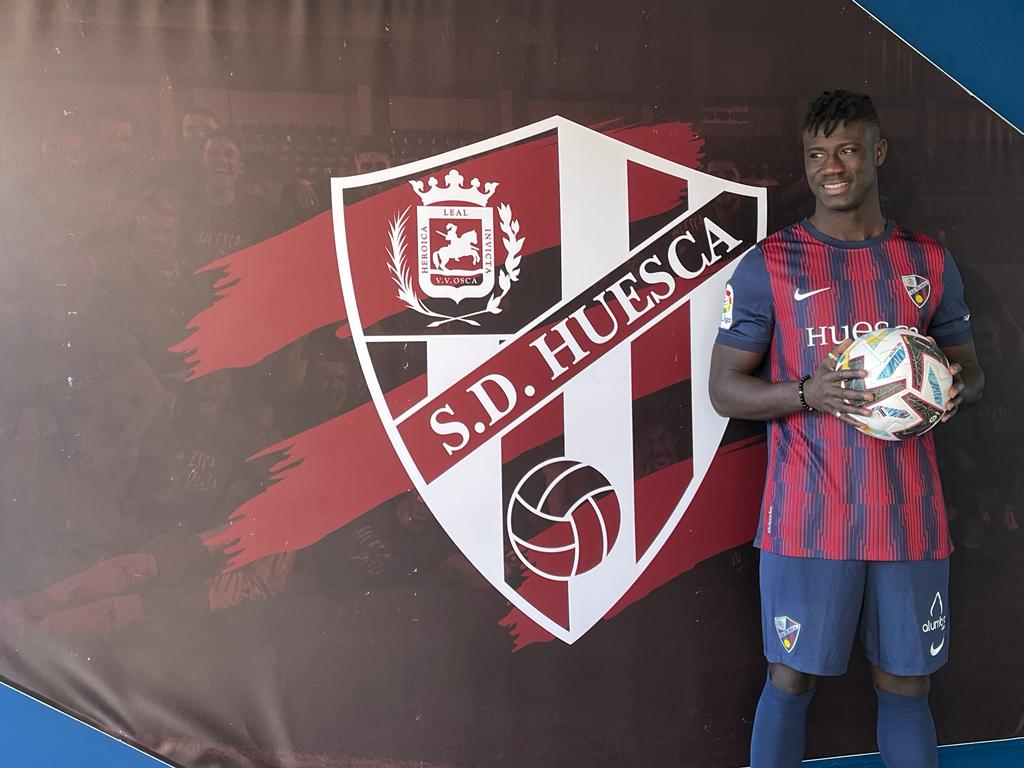 Samuel Obeng posa junto al escudo del Huesca en el túnel de vestuarios de El Alcoraz. Foto: Adrián Mora