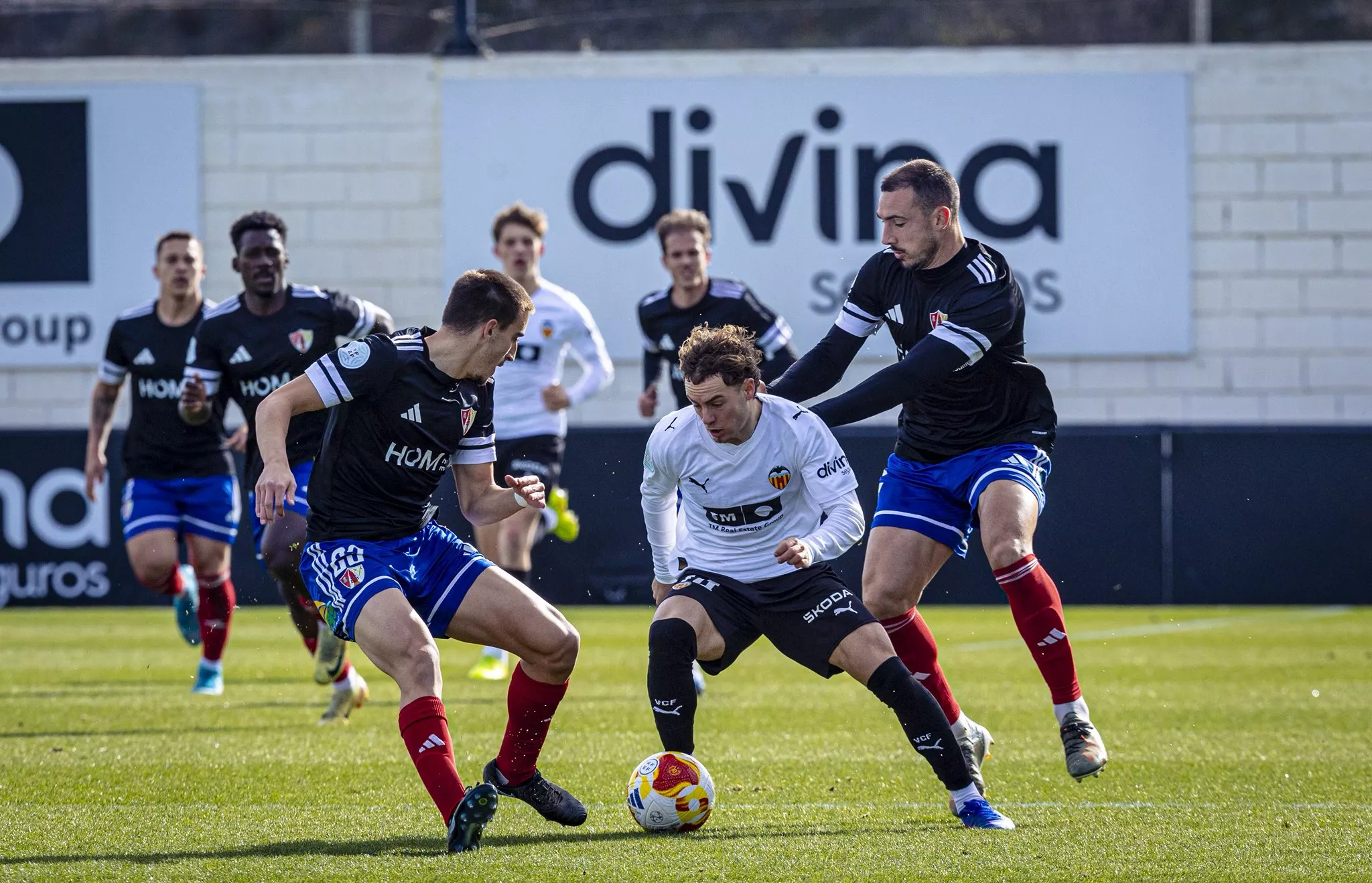 Alarcón y Mingotes enciman a un jugador del Valencia Mestalla. Foto: Valencia CF