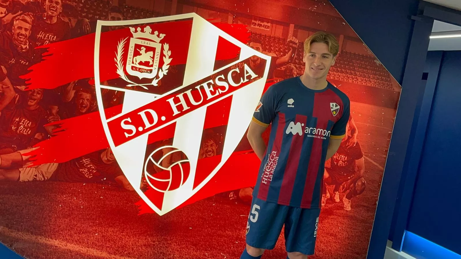 Álex Cantero posa junto al escudo del Huesca este martes en el túnel de El Alcoraz. Foto: Adri Mora