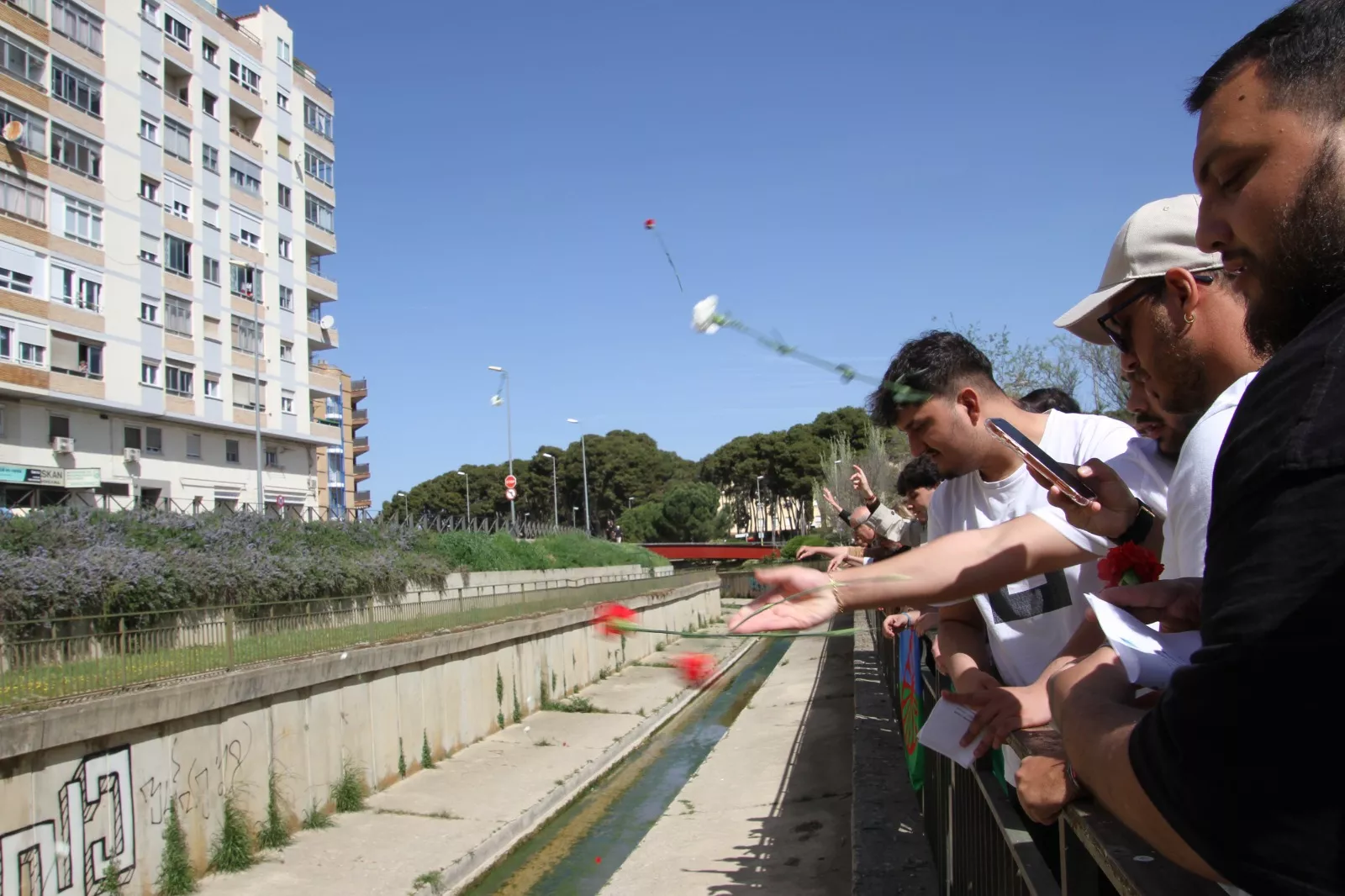 Los participantes en el Día Internacional del Pueblo Gitano arrojan los claveles al cauce del río Isuela. Foto Carlos Neofato
