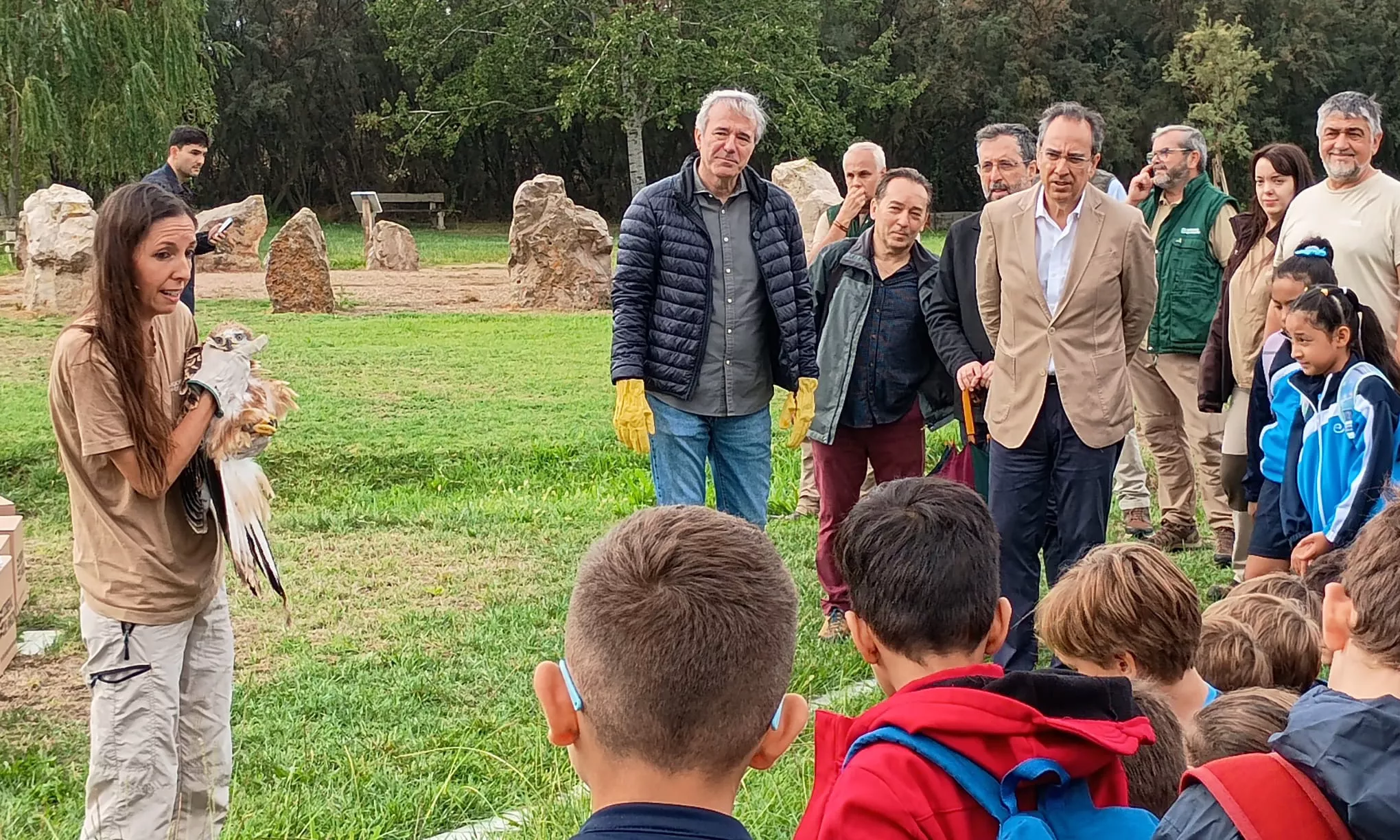 Técnico Ambiental de La Alfranca ofrece explicaciones a autoridades y niños asistentes mientras sotiene un milano real momentos antes de su liberación.