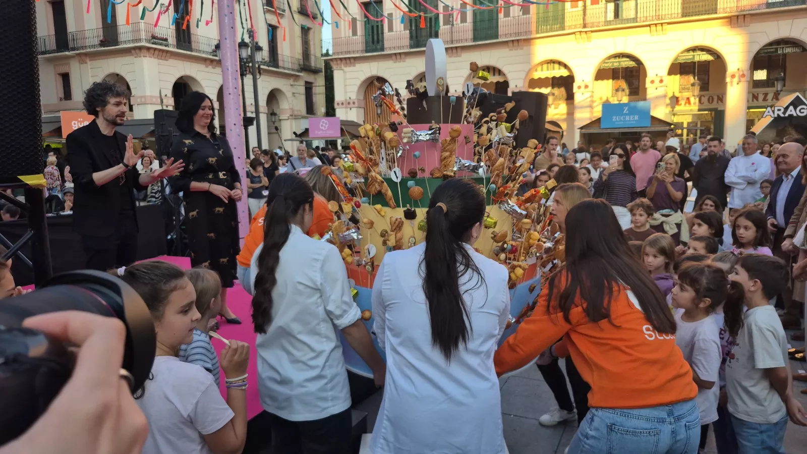 Lorena Orduna observa a los niños abalanzarse sobre la simulación de tarta cargada de chucherías y pastas en la Feria Huesca es Dulce