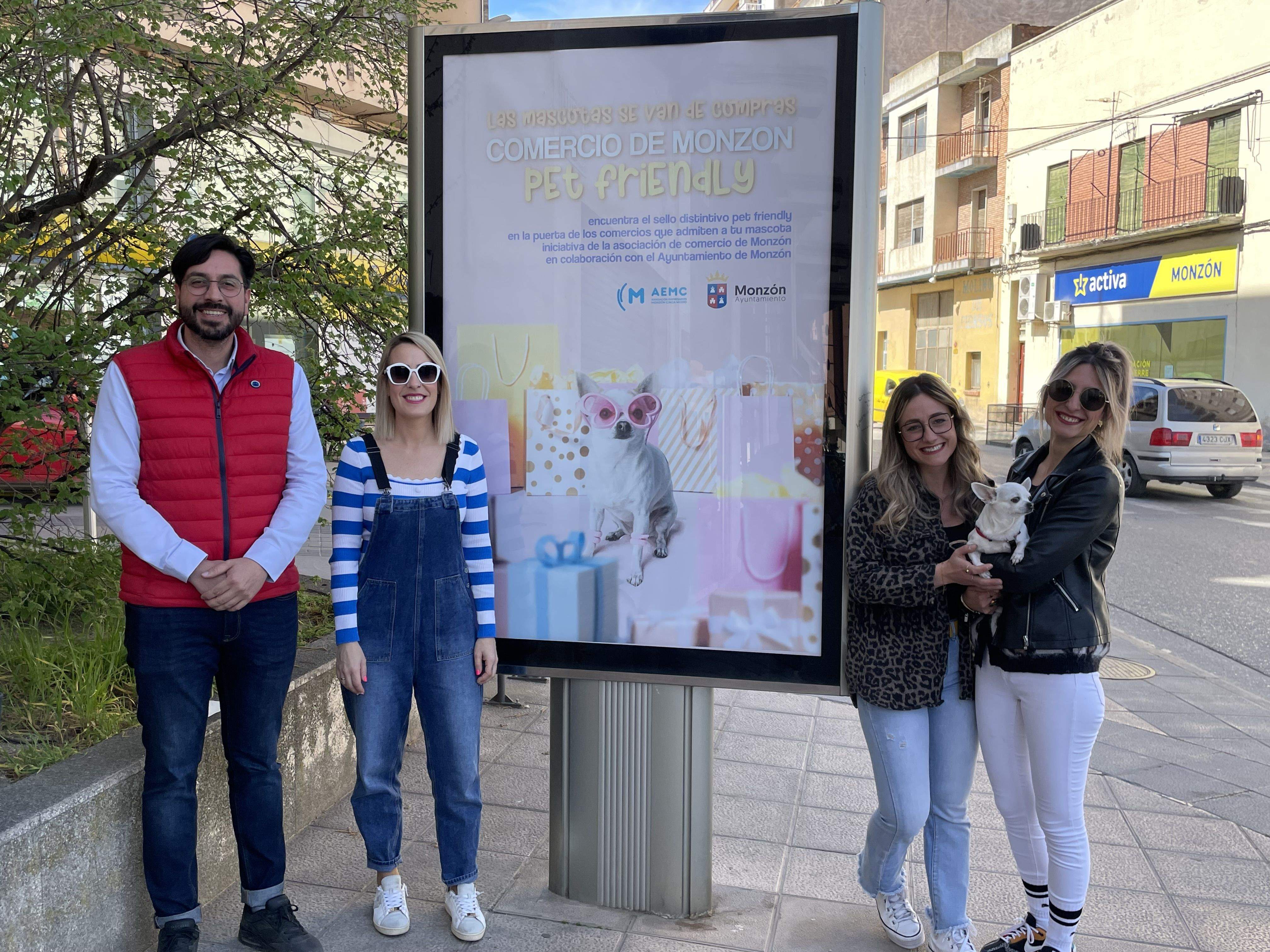Los protagonistas de la presentación de la campaña "Las mascotas se van de compras" junto a uno de los mupis.