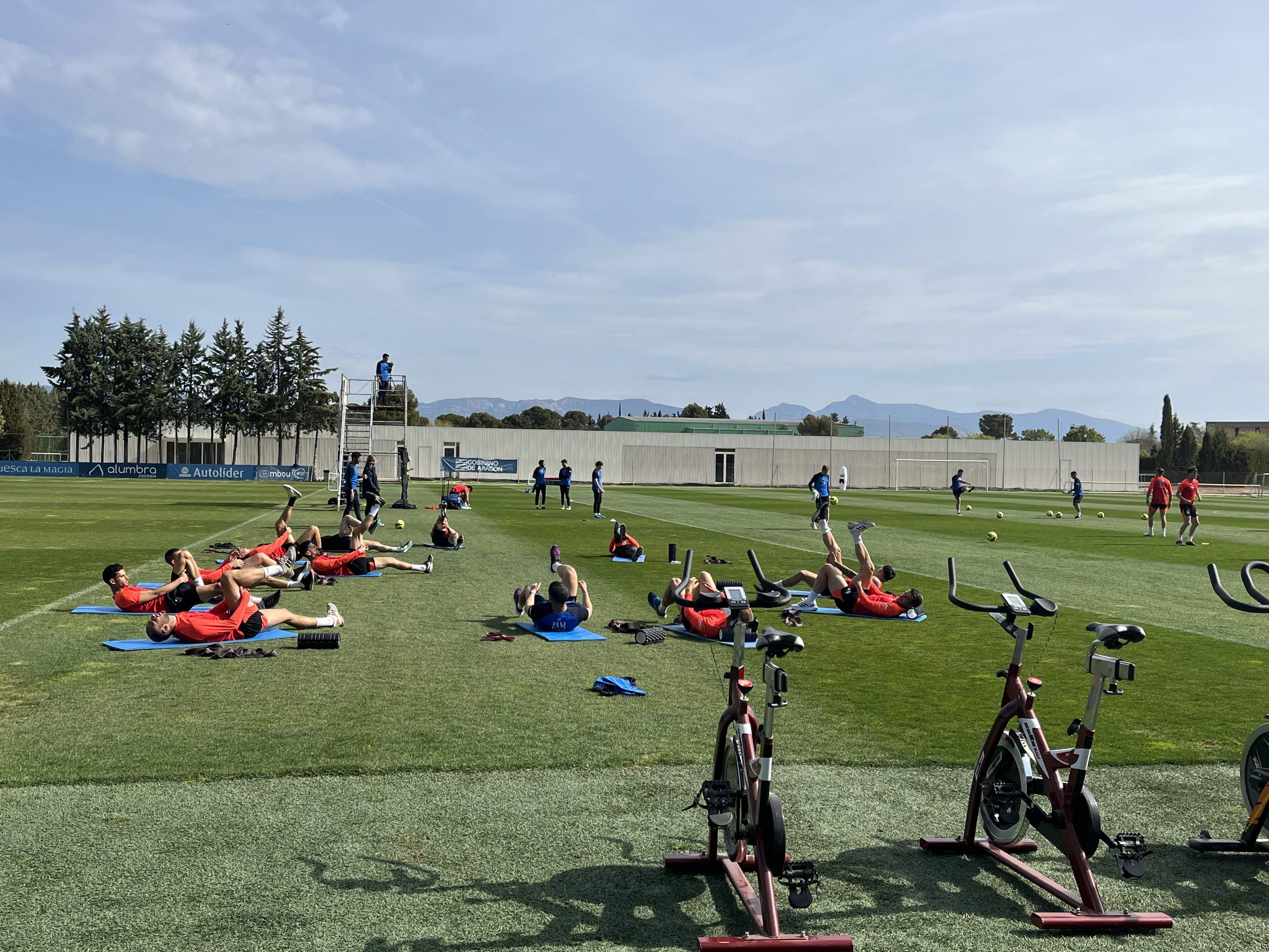 Los jugadores del Huesca que fueron titulares este domingo realizan estiramientos en el IES Pirámide. Foto: Adrián Mora