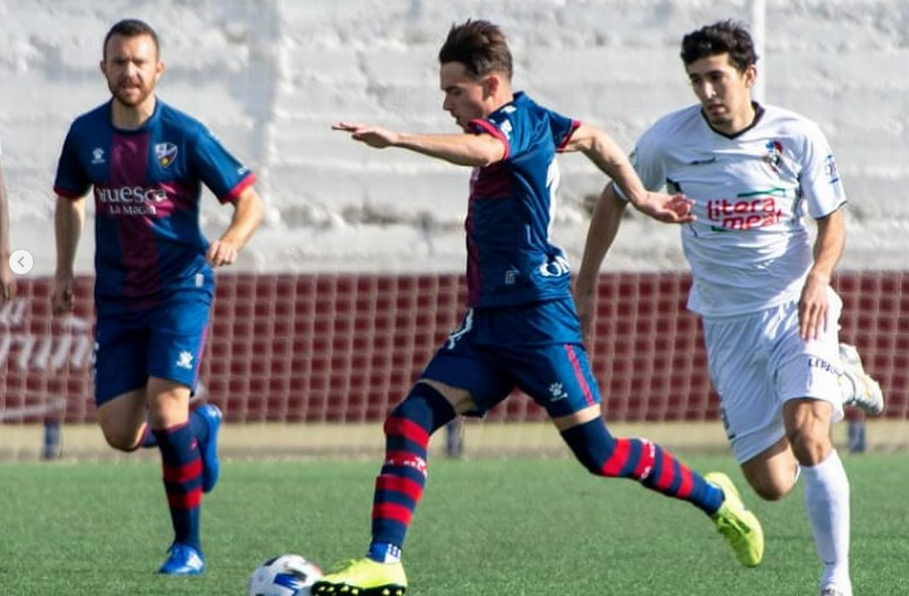Gus Abizanda conduce un balón con la camiseta del Huesca B y al fondo Fer Arnedillo, actual jugador del Barbastro. Foto: Guara Fotografía