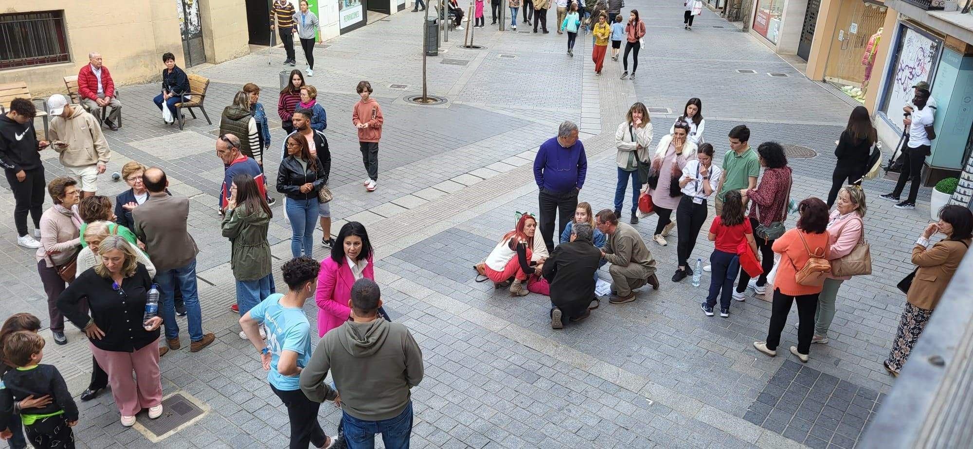 Cuatro personas atienden agachadas a la víctima del atropello en el Coso Alto de Huesca.
