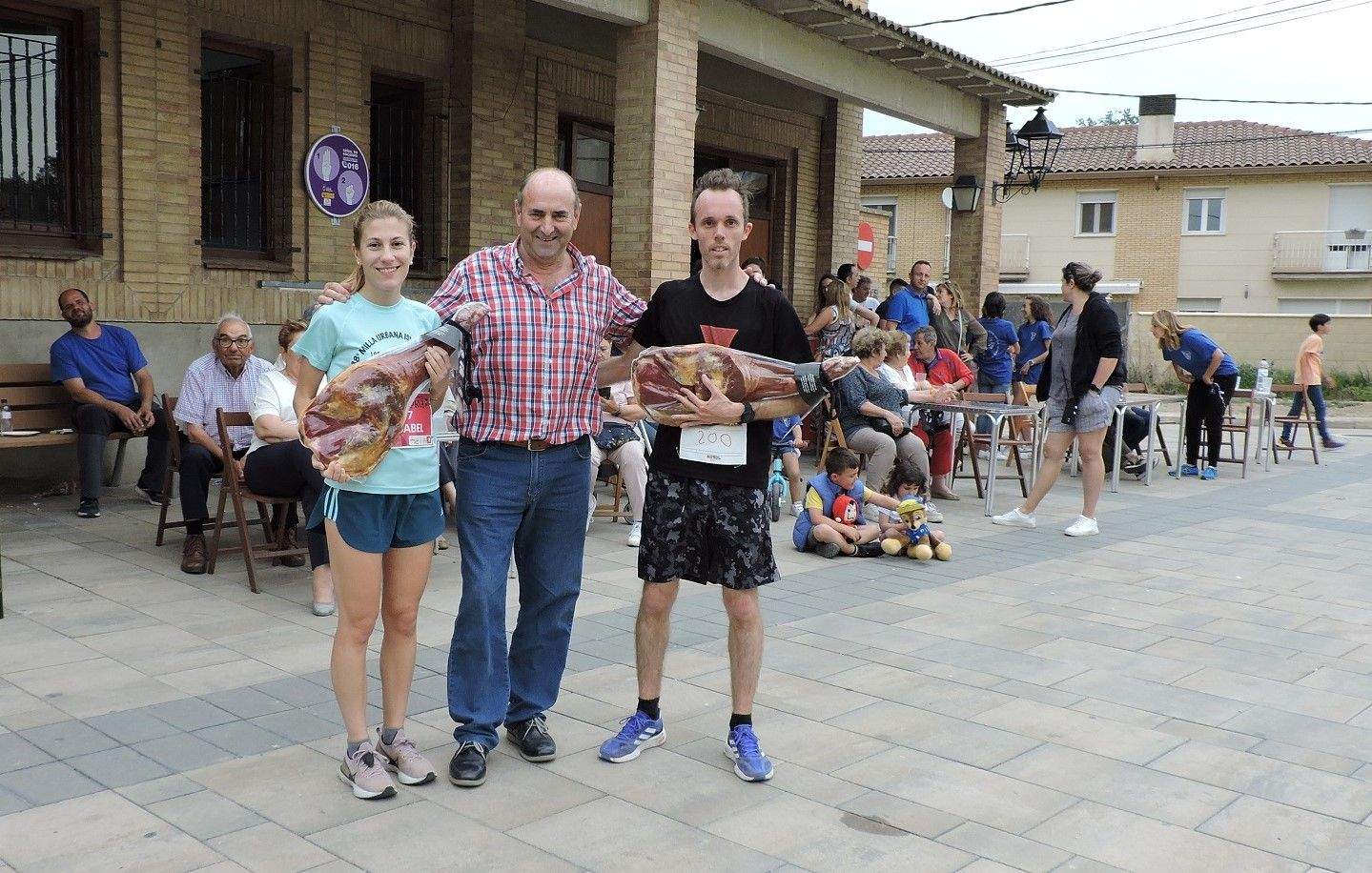 Isabel Linares y Javier Castells posan junto al alcalde del Pueyo de Santa Cruz con el jamón de los ganadores.