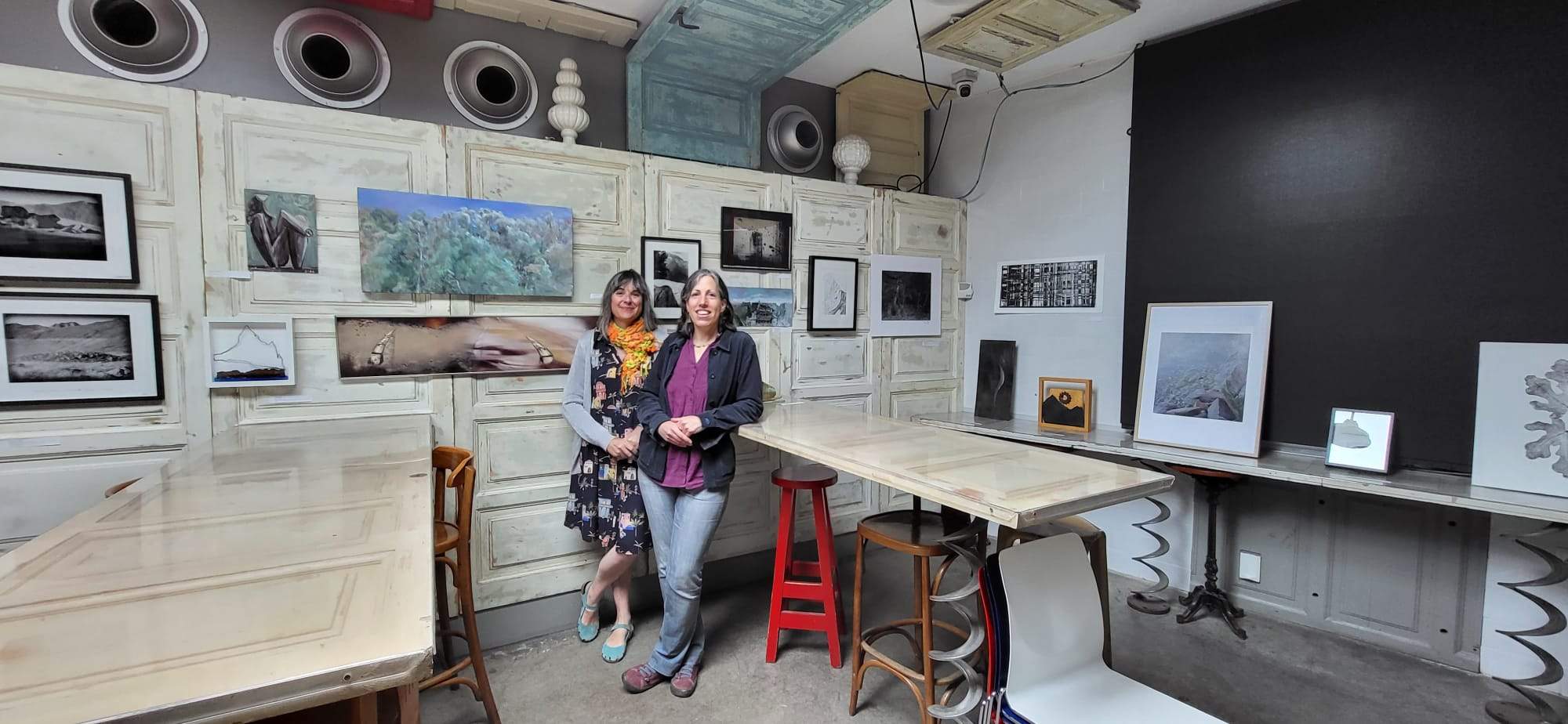 Teresa Abad y Beatriz Aísa junto a parte de las obras que se van a subastar.