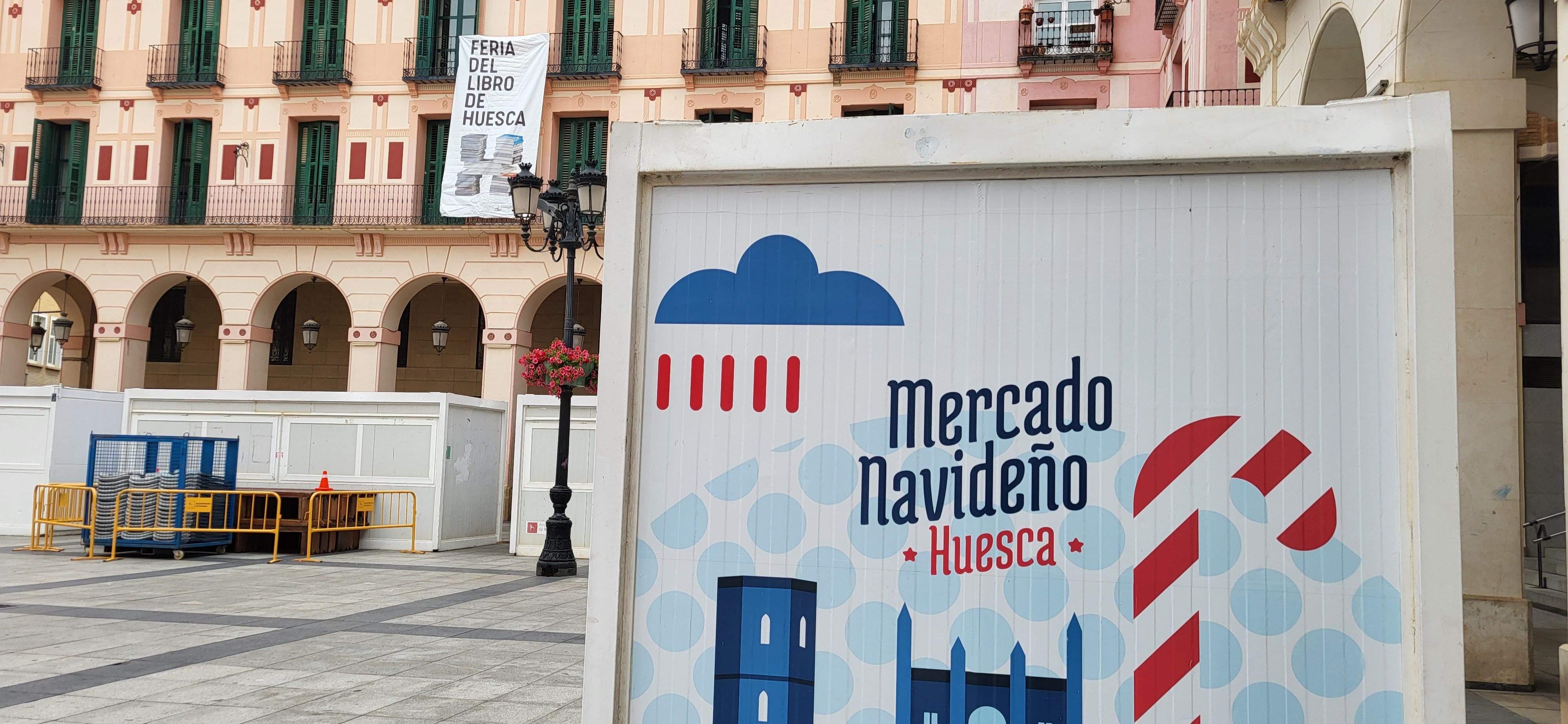 En el balcón de Ceoe-Cepyme Huesca, la banderola de la Feria del Libro. En primer plano, vinilo del Mercado Navideño.
