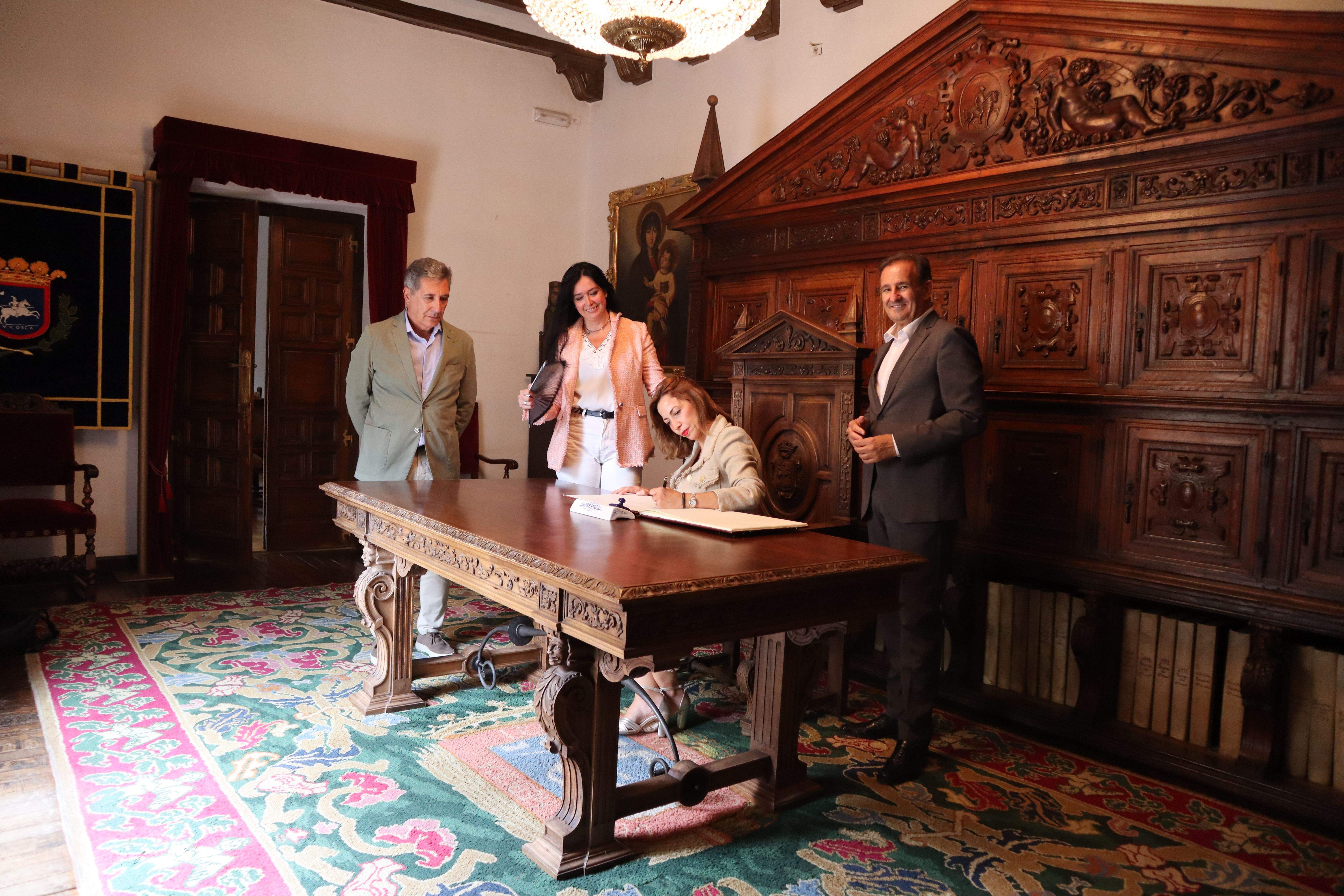 Natalia Chueca firma en el libro de honor del ayuntamiento de Huesca ante la mirada de Lorena Orduna